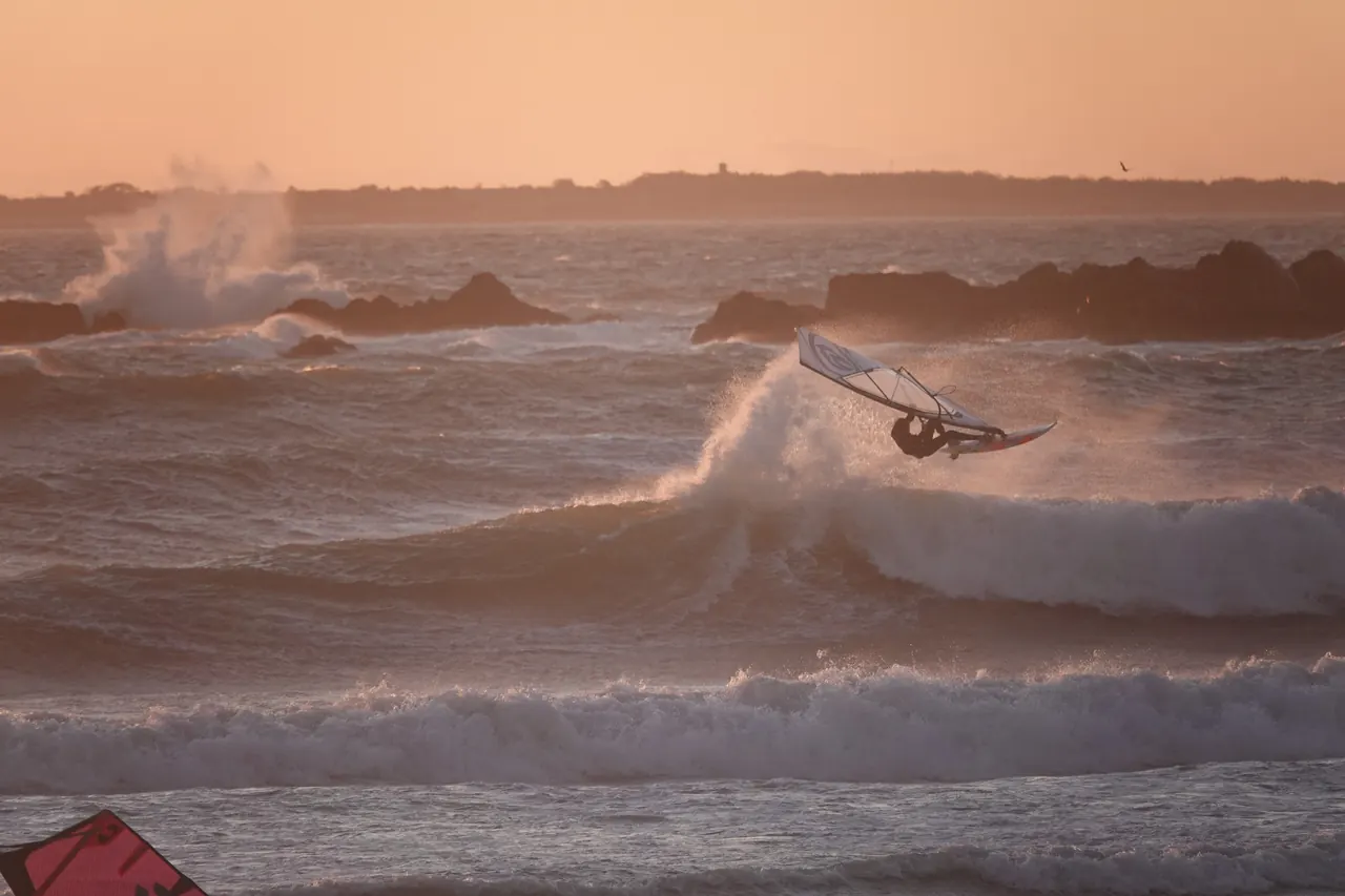 Windsurfer springt bij zonsondergang