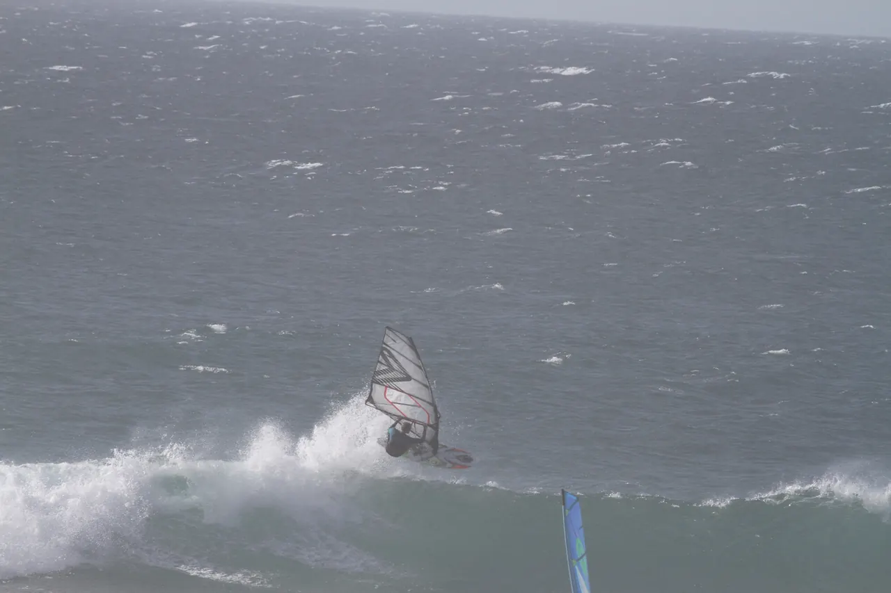 Windsurfer op een golf in grijs weer