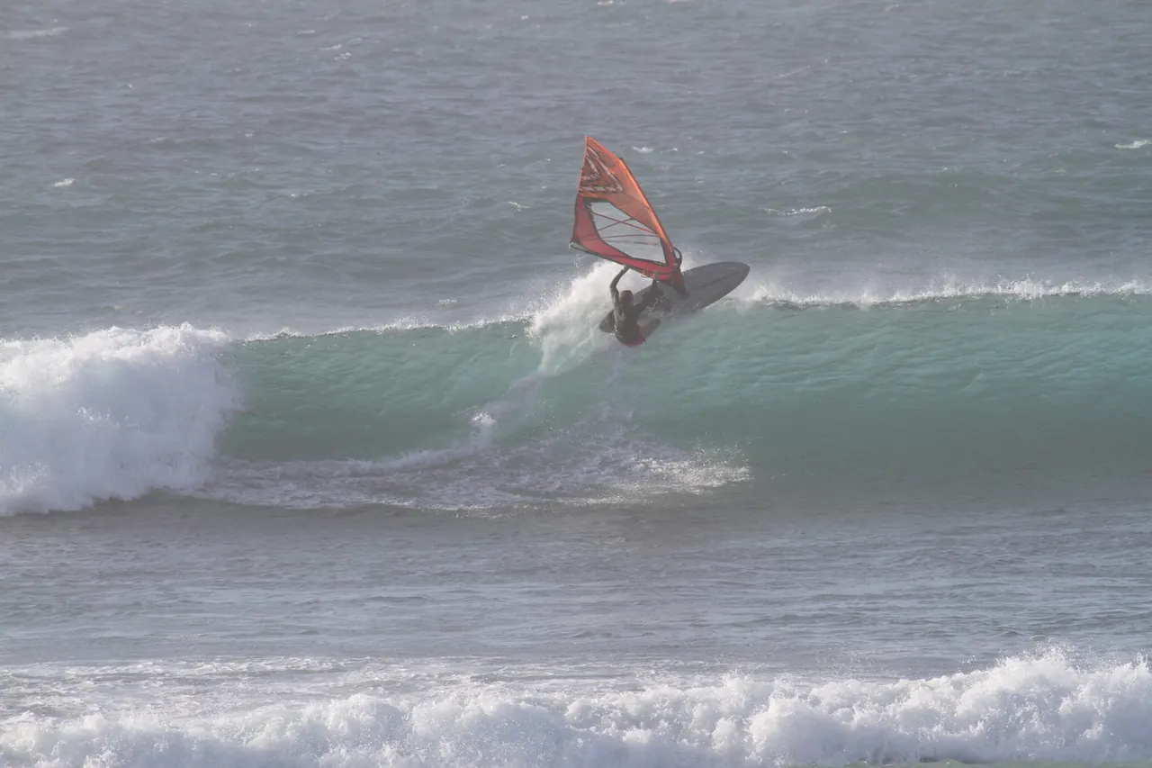 Windsurfer snijdt door de groene golf