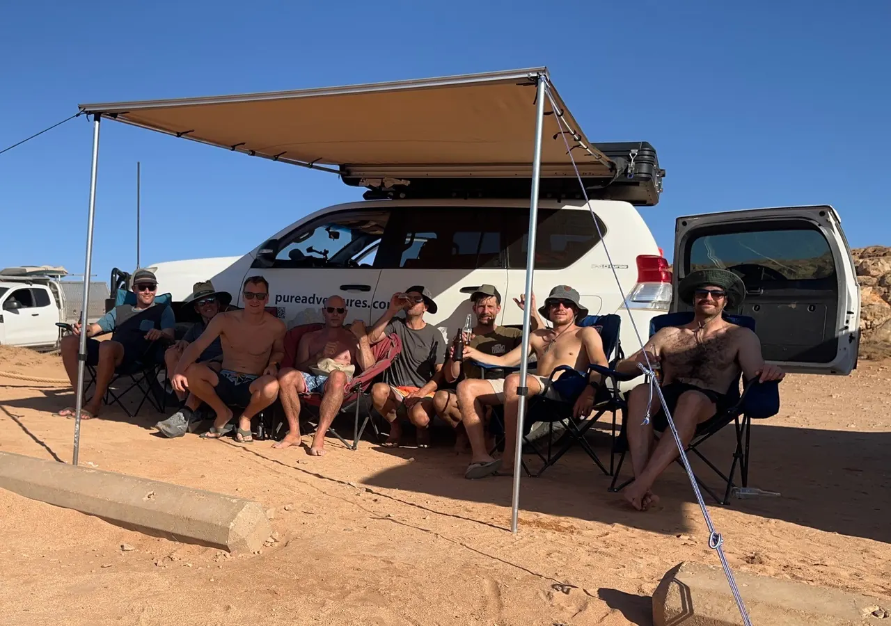 De crew onder de luifel naast de 4x4 in de woestijn